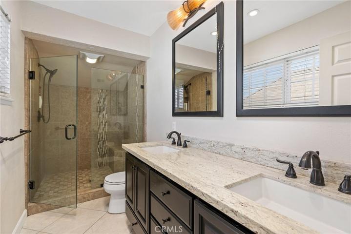 Relax in the luxurious en-suite bathroom with porcelain tile floors, dual vanity sinks, quartz countertops, and a step-in shower!