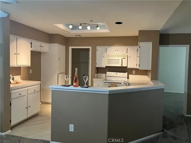 Open space kitchen with track lighting, new flooring, new cabinetry hardware, and more.