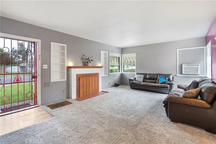 Spacious living room with corner windows, original hardwood floors underneath carpeting, and wood-burning fireplace.