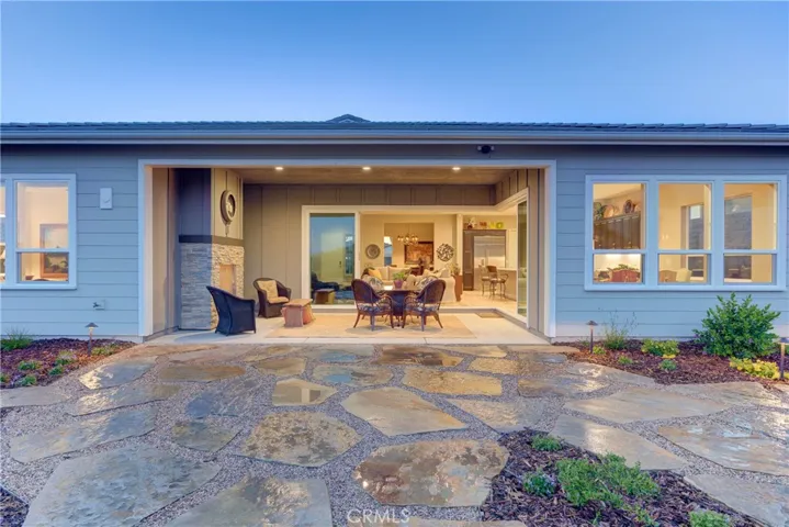Night view looking down to the extended stone patio, covered patio with fireplace and into dining room on the right and great room straight ahead