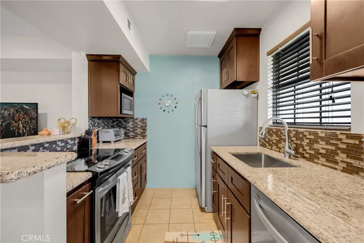Remodeled Kitchen with Stainless Steel Appliances, Espresso Cabinetry, & Glass Tiled Backsplash