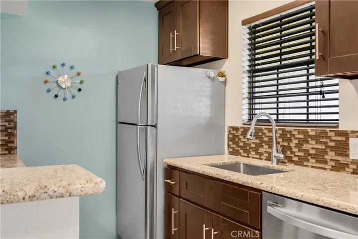 Remodeled Kitchen with Stainless Steel Appliances, Espresso Cabinetry, & Glass Tiled Backsplash