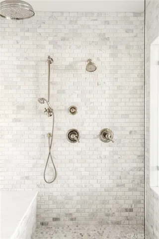 Marble Tile shower with three shower heads.