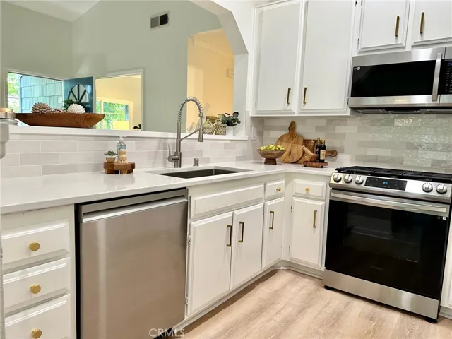 New quartz countertop, large stainless steel sink with new faucet and appliances in kitchen