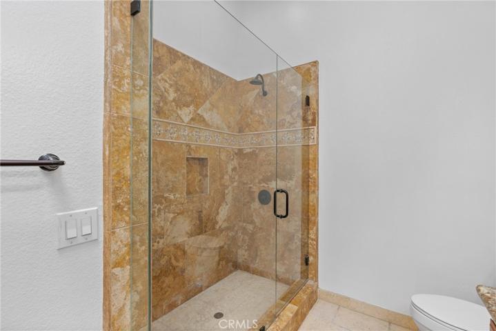 Glass-enclosed step-in shower with travertine walls and floors!