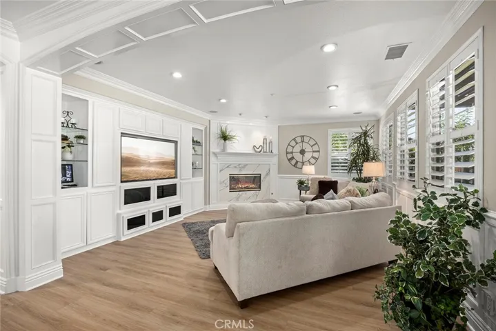 Family room has Quartz Fireplace with custom mantle, crown molding which is thru-out the home. Wainscoting, custom built-ins with glass display cabinets and storage. Surround Sound & Camera system for the home are housed in here.