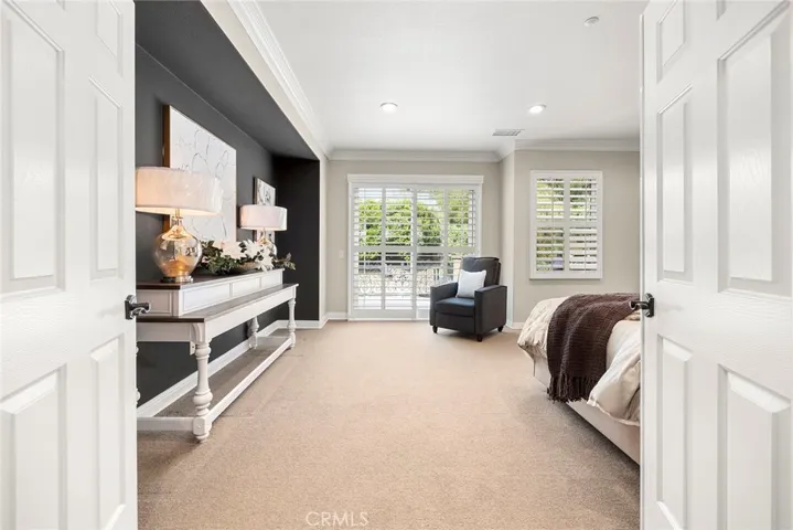 Primary bedroom looking out to expansive walk out deck with spiral staircase, and elaborate scrolled wrought iron fencing