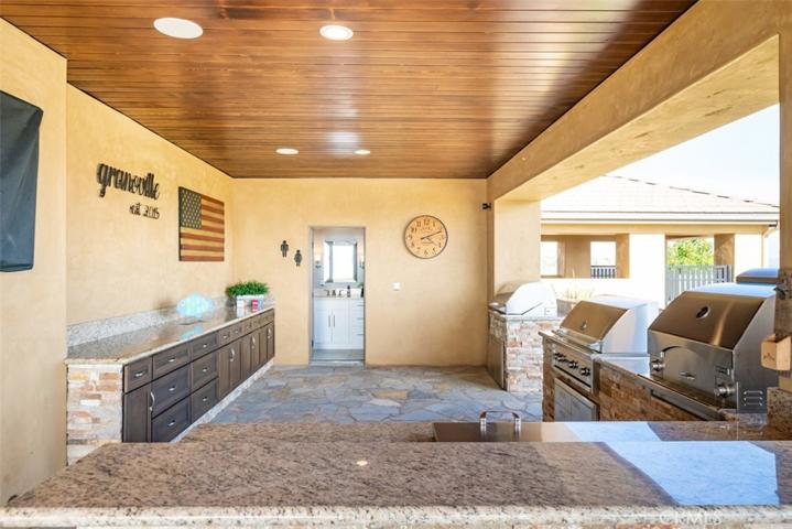 Outdoor kitchen area with custom cabinetry leading to Pool Bathroom