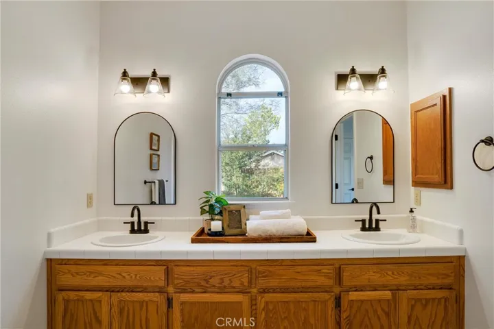 Double vanity in primary bathroom. New faucets, lighting and mirrors. Bathtub/shower combo also has new fixtures.