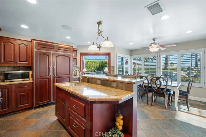 Built-in Sub-Zero with cabinet door facing, island, and breakfast nook.