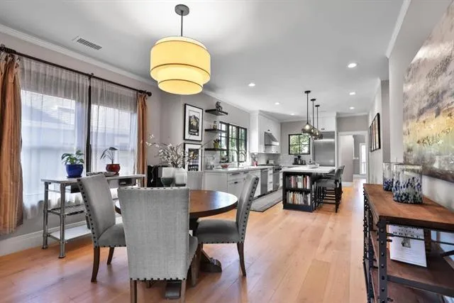 Dining area with designer light fixture, high ceilings, and large windows.