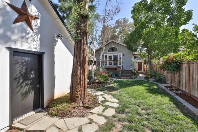 Side entrance to large garage with workshop areas; stone pathway and lovely redwood tree.