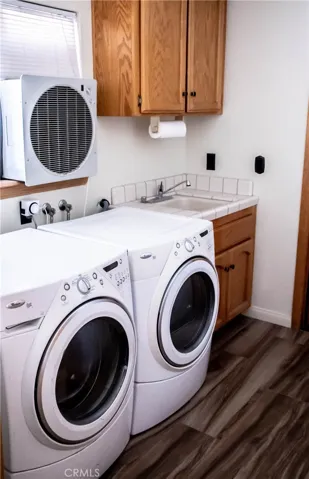 Indoor laundry with wash sink, wood grain tile floors and cooler.