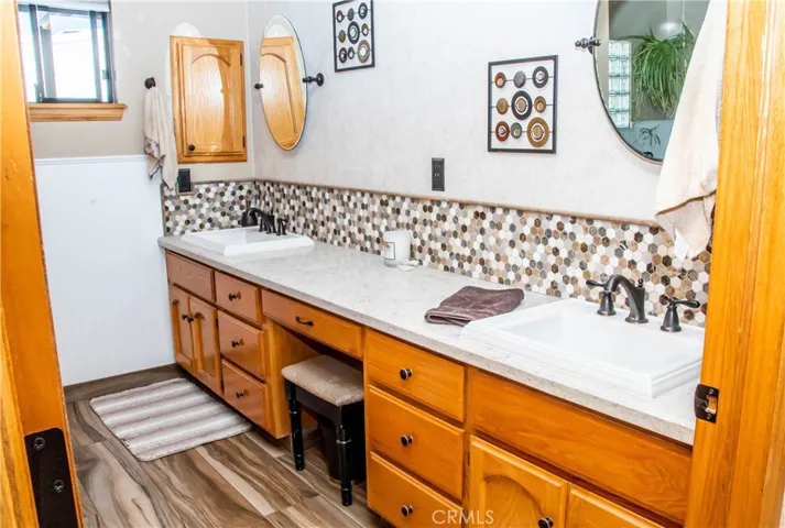 Master/primary bedroom on-suite bath with dual vanities, custom tile backsplash, wood grain tile floors, free standing tub and separate shower.