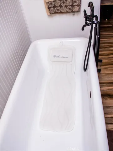 Master/primary free standing tub.  Bathroom also includes dual vanities, custom tile backsplash, wood grain tile floors, free standing tub and separate shower.