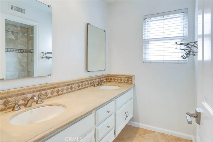 Second upstairs bathroom with stone counter tops and dual vanities.