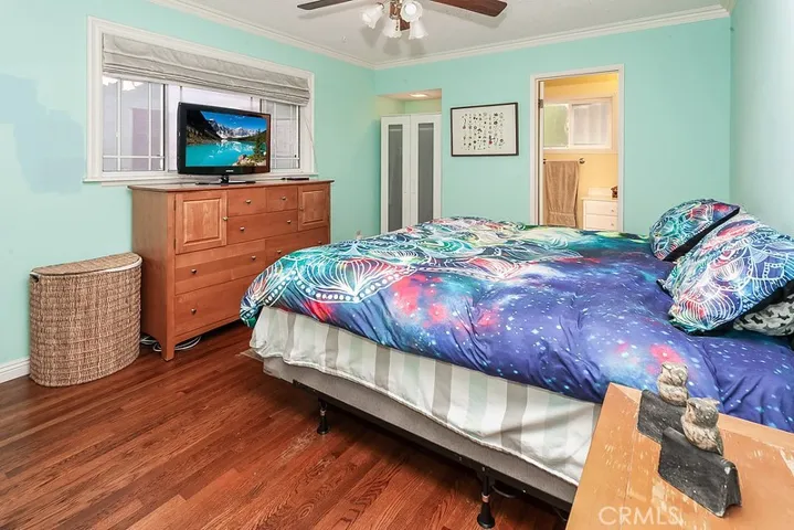 The primary suite is enriched by a gleaming window, crown molding, lighted ceiling fan, ample closet space and complementary hardwood floors.