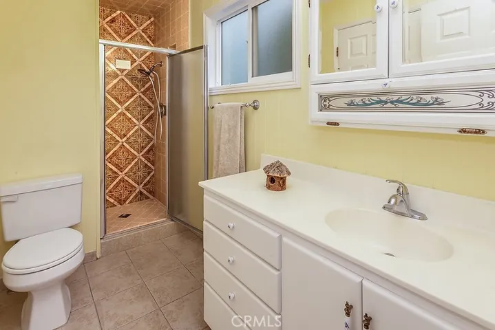 Private en suite primary bathroom with crown molding, white vanity, dressing mirror with sundry storage and glass enclosed step-in shower.