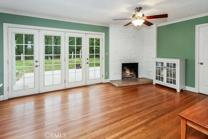 The family room with its elegant crown molding, lighted ceiling fan, floor-to-ceiling raised hearth brick fireplace, and French doors that lead to the backyard is great for family gatherings or quiet relaxation.