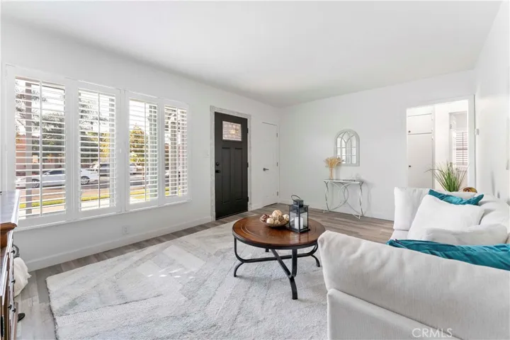 Formal living lovingly updated with luxury vinyl plank flooring and double pane windows and door/screen door and paint. Throughway (right) to small hallway to the bedrooms and one of the bathrooms