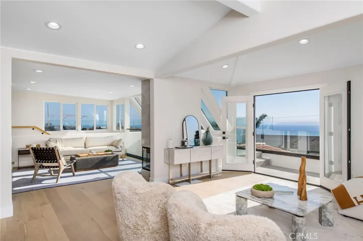 Upstairs, dramatic ocean, coastline and city-light views shine through an abundance of windows that illuminate a living room, dining room.