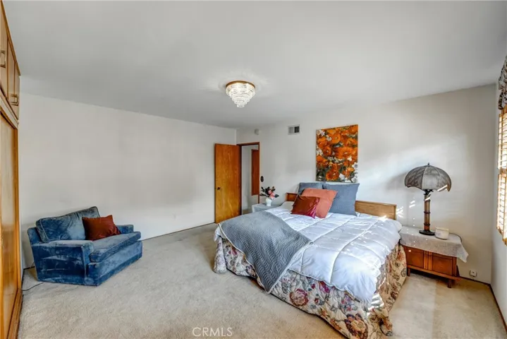 SPACIOUS PRIMARY BEDROOM WITH CUSTOM SHUTTERS AND EN SUITE BATH, ORGINAL HARDWOOD FLOORS UNDER CARPET