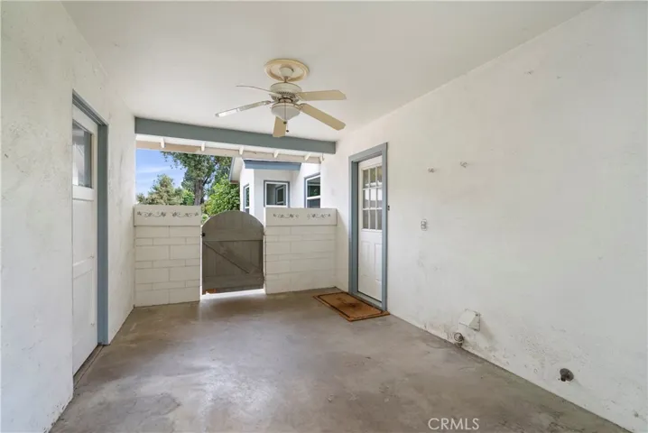 Covered breezeway between house and garage with gate and ceiling fan.