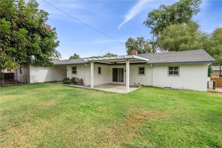 Pool-size backyard with newer patio cover and dog kennel to the far left under the tree.