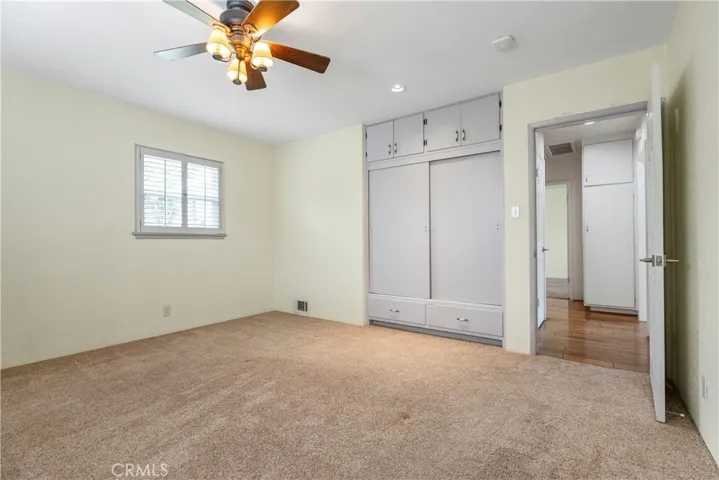 Bedroom #2 with plantation shutters on the windows, and a ceiling fan.