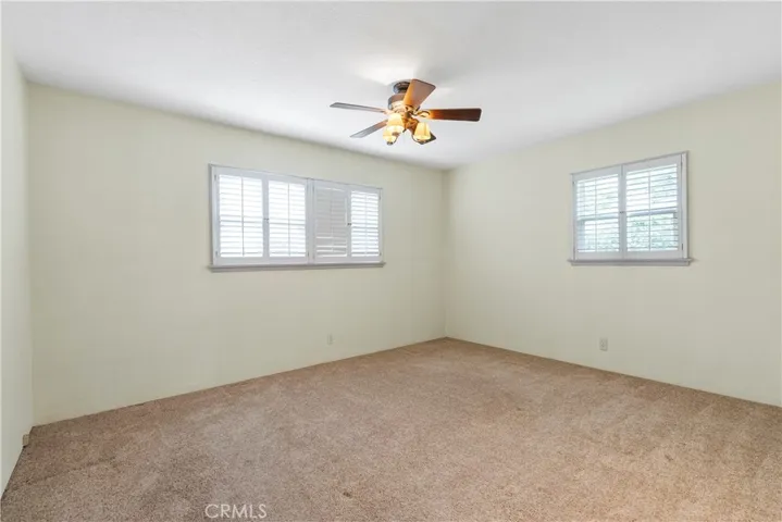 Alternate view of Bedroom #2 with plantation shutters and ceiling fan.