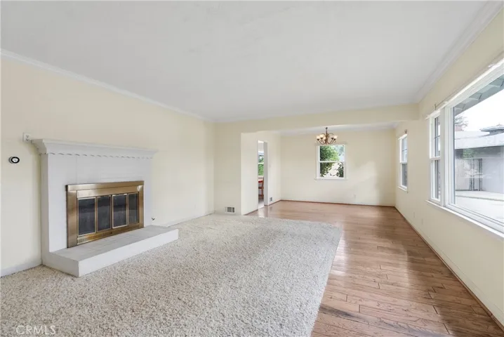 View of living room as you enter the home, with wood flooring leading your way into the formal dining room.