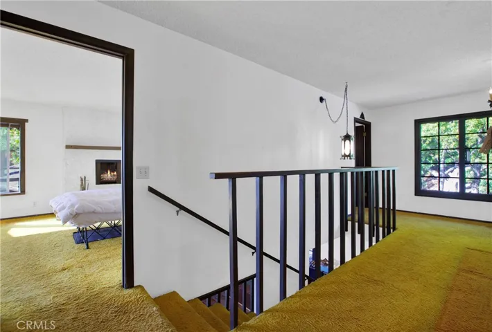 Second level hallway and view into primary bedroom with fireplace.
