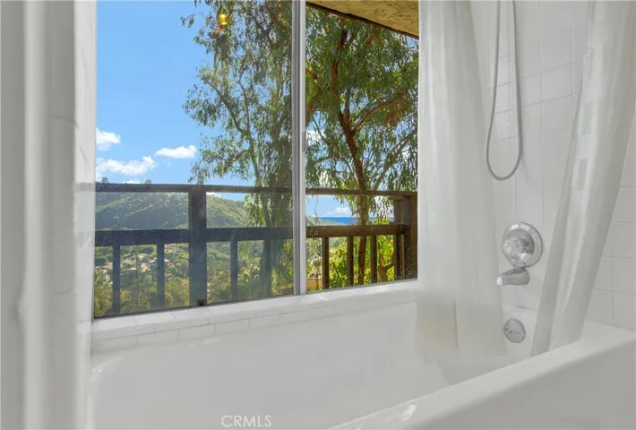 Primary bath with tub in shower and ocean views.