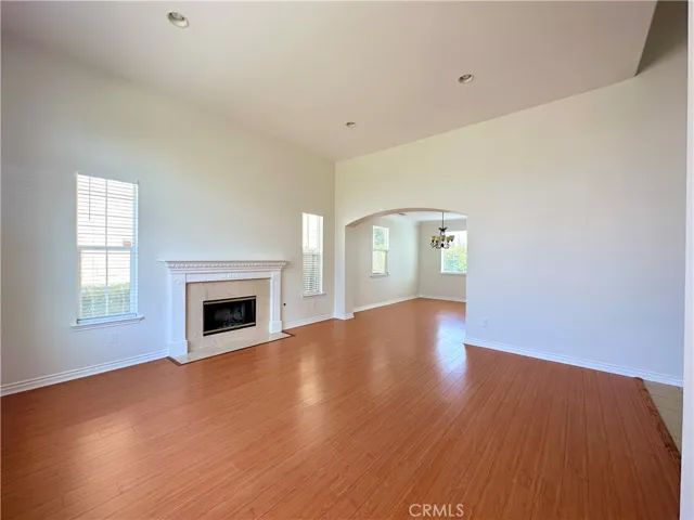 Large living room with central focal fireplace, decorative mantle. Beautiful laminate floors. Fresh paint and  all new window coverings