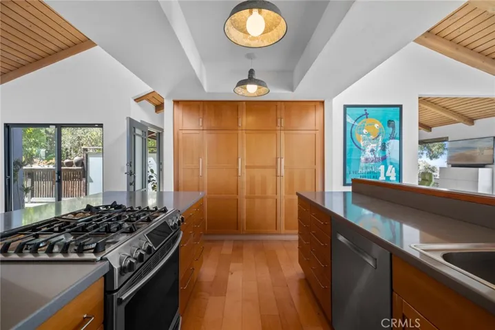 An open-concept gourmet kitchen features wood and glass cabinetry, a spacious pantry, solid-surface countertops.