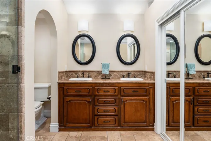 Primary bathroom with heated travertine stone floors, dual vanity and two closets.