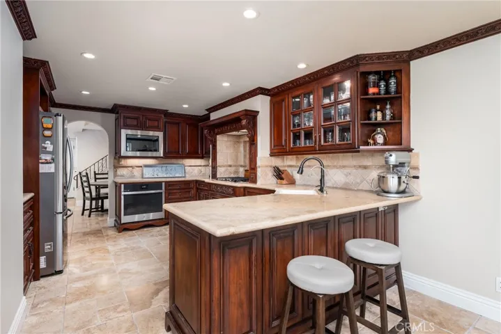 Custom kitchen with solid cherry wood cabinetry, tumbled travertine floor and newer stainless steel appliances.
