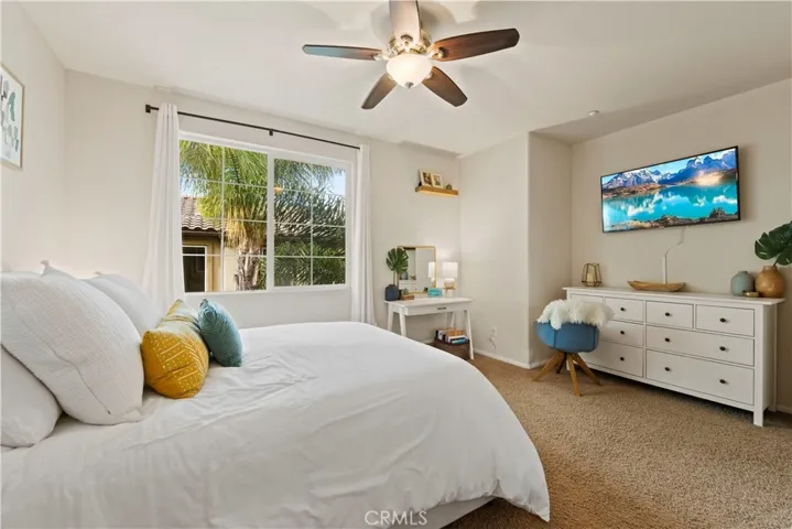 Primary bedroom is bright, has a ceiling fan, & is carpeted.