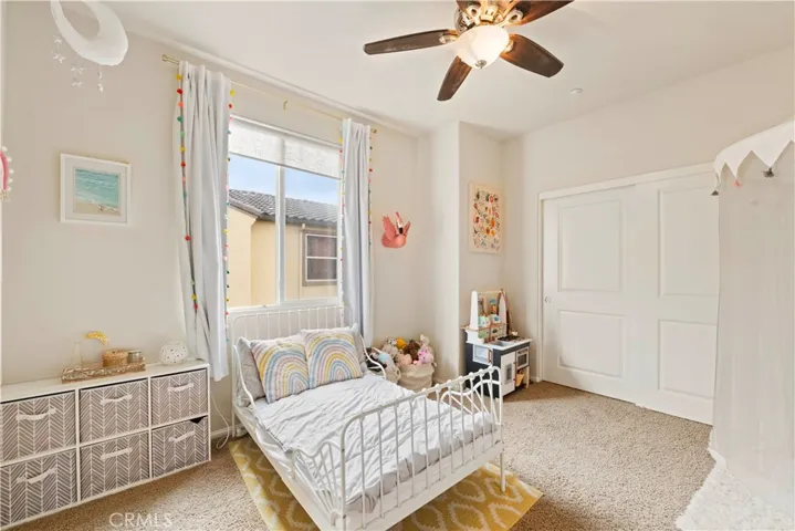The secondary bedroom has one wide closet on one wall, is capreted and also has a ceiling fan.