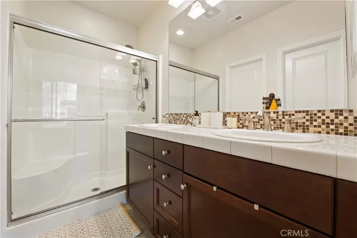 The Primary Bathroom has upgraded cabinetry, tile counters, & backsplash. The walk in closet is accessible from this restroom.