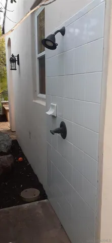 Outdoor shower located on the backside of the  backyard structure containing bathroom and storage room.