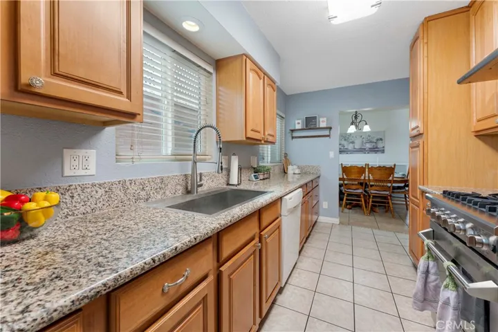 Galley kitchen with granite counters and plenty of cabinets for storage. Window view of side yard with block wall that has a painted mural.