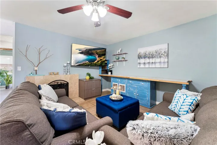 Spacious living room with ceiling fan and fireplace makes for cozy ambiance.