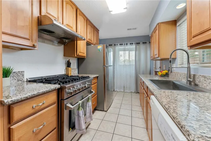 Galley kitchen with granite counters and plenty of cabinets for storage. The indoor laundry is at the end of the kitchen (behind curtain) that has a window view of the front yard. Side door to the right (not seen but at the end of the counter before the laundry).