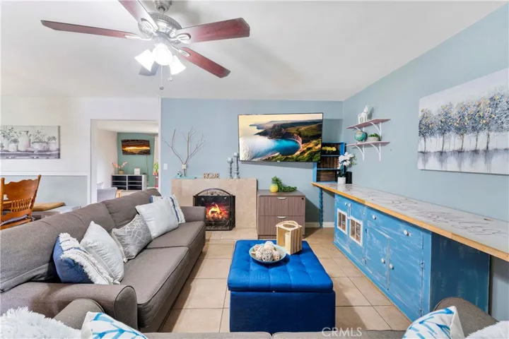 Living room with ceiling fan and fireplace. The throughway to the left is a family room with French doors to the backyard (not in image) Left of image is the dining area.