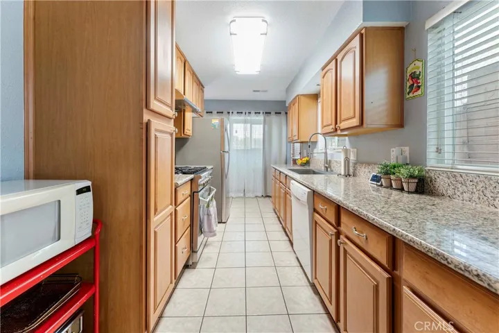 Galley kitchen with granite counters and plenty of cabinets for storage. The indoor laundry is at the end of the kitchen (behind curtain) that has a window view of the front yard. Side door to the right (not seen but at the end of the counter before the laundry).