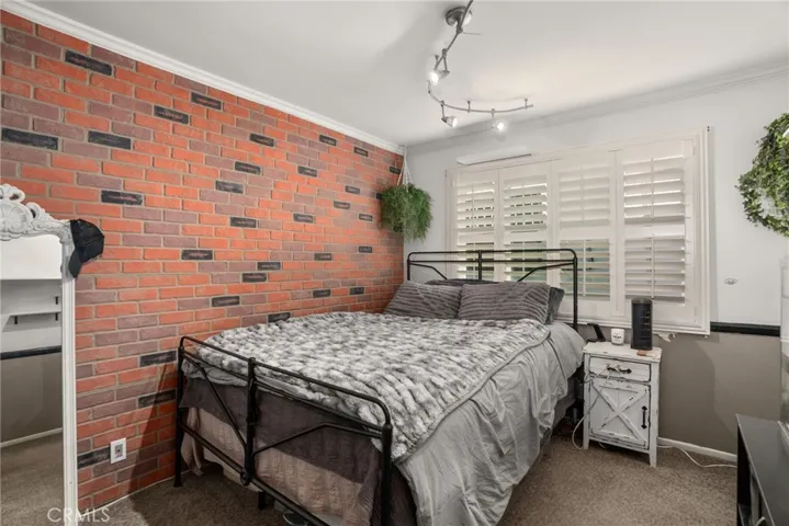 Guest Bedroom with shutters, brick wall cover, and carpet.