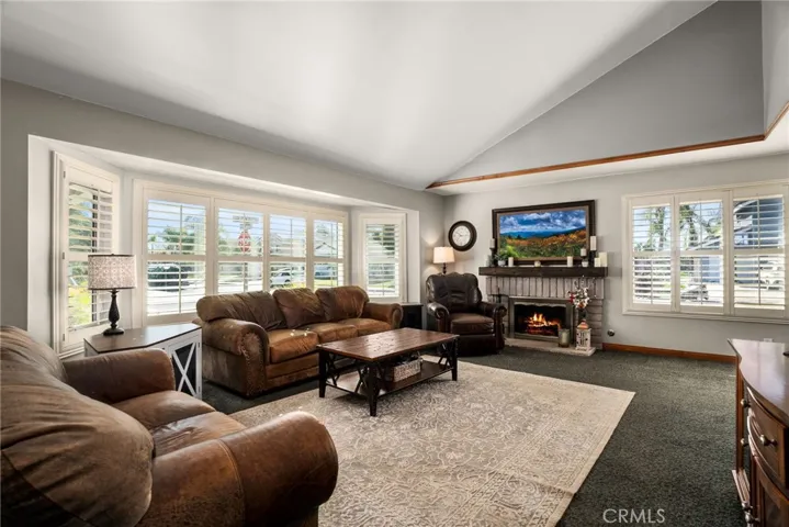 Living room with high ceilings, gas fireplace, and plantation shutters.