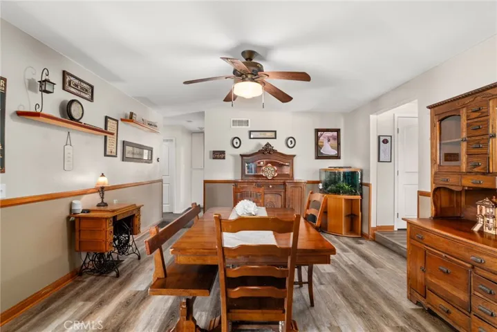 Dining room with wood floors and a ceiling fan.