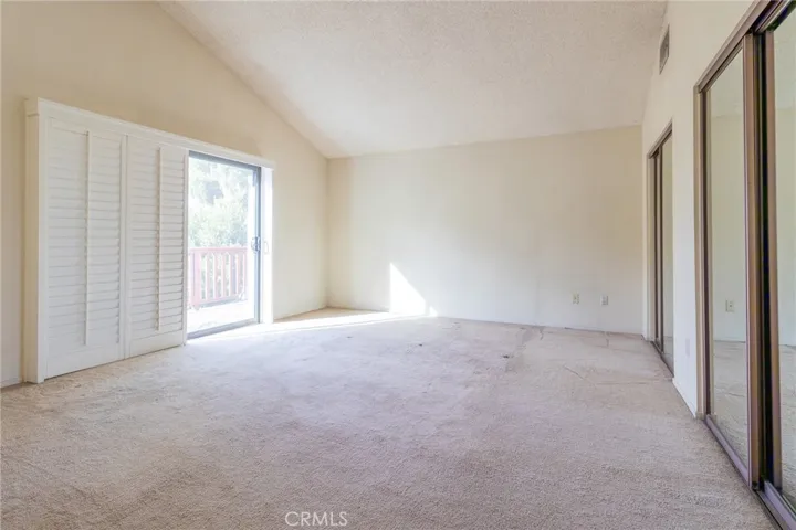 Primary bedroom with view towards balcony area.